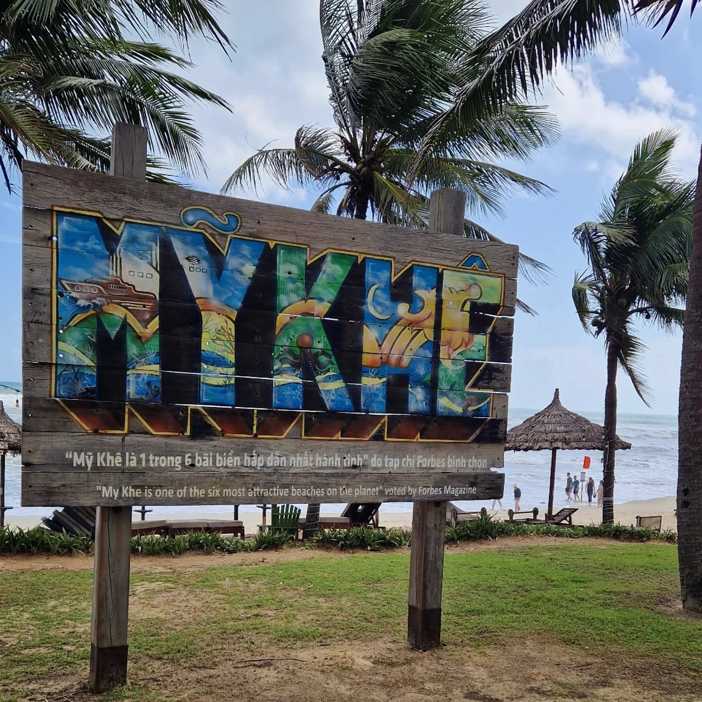 Carved "MY KHE" sign quoting Forbes on the beach