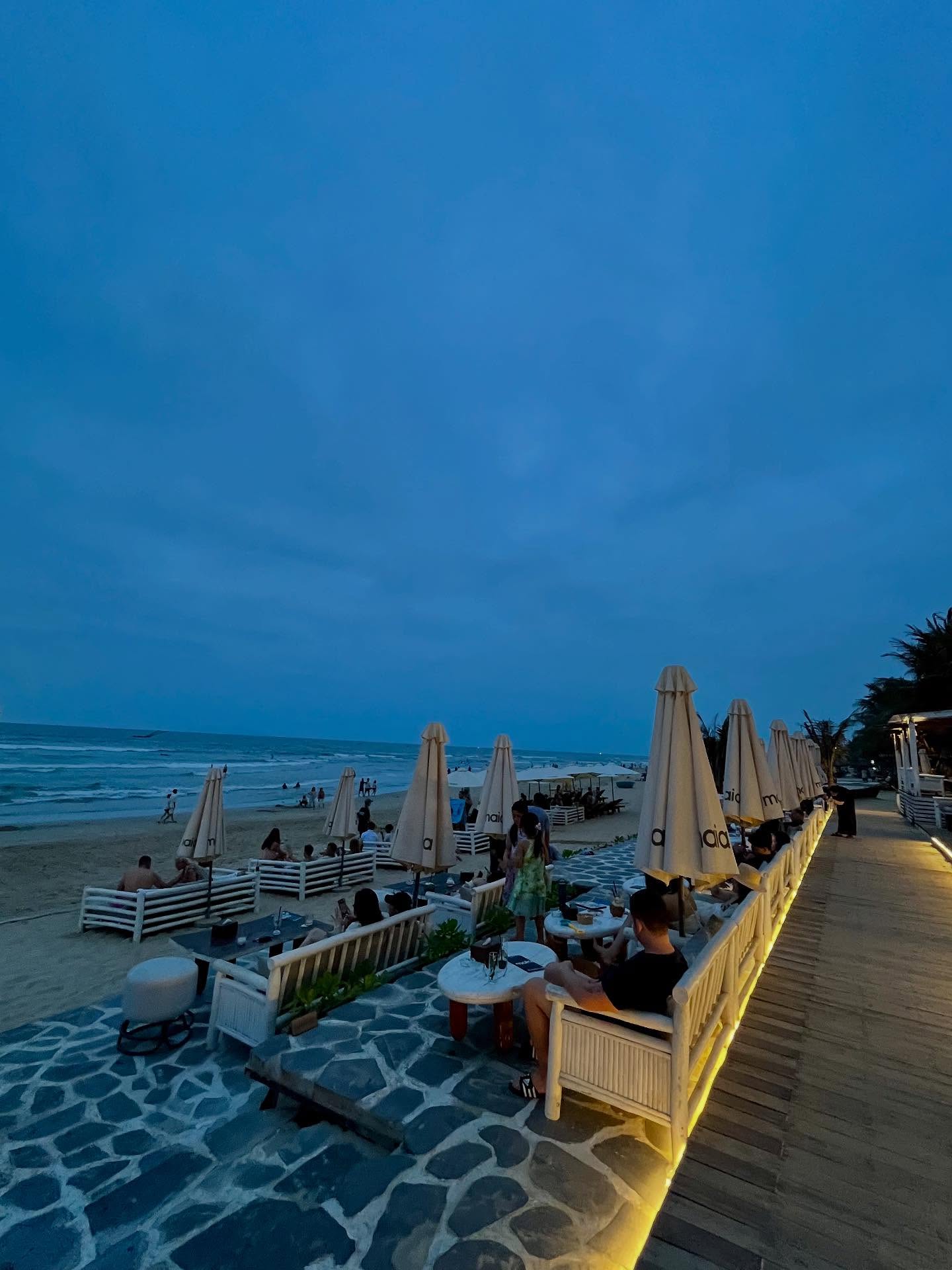 Row of Maia's beach benches and parasols along the boardwalk at dusk