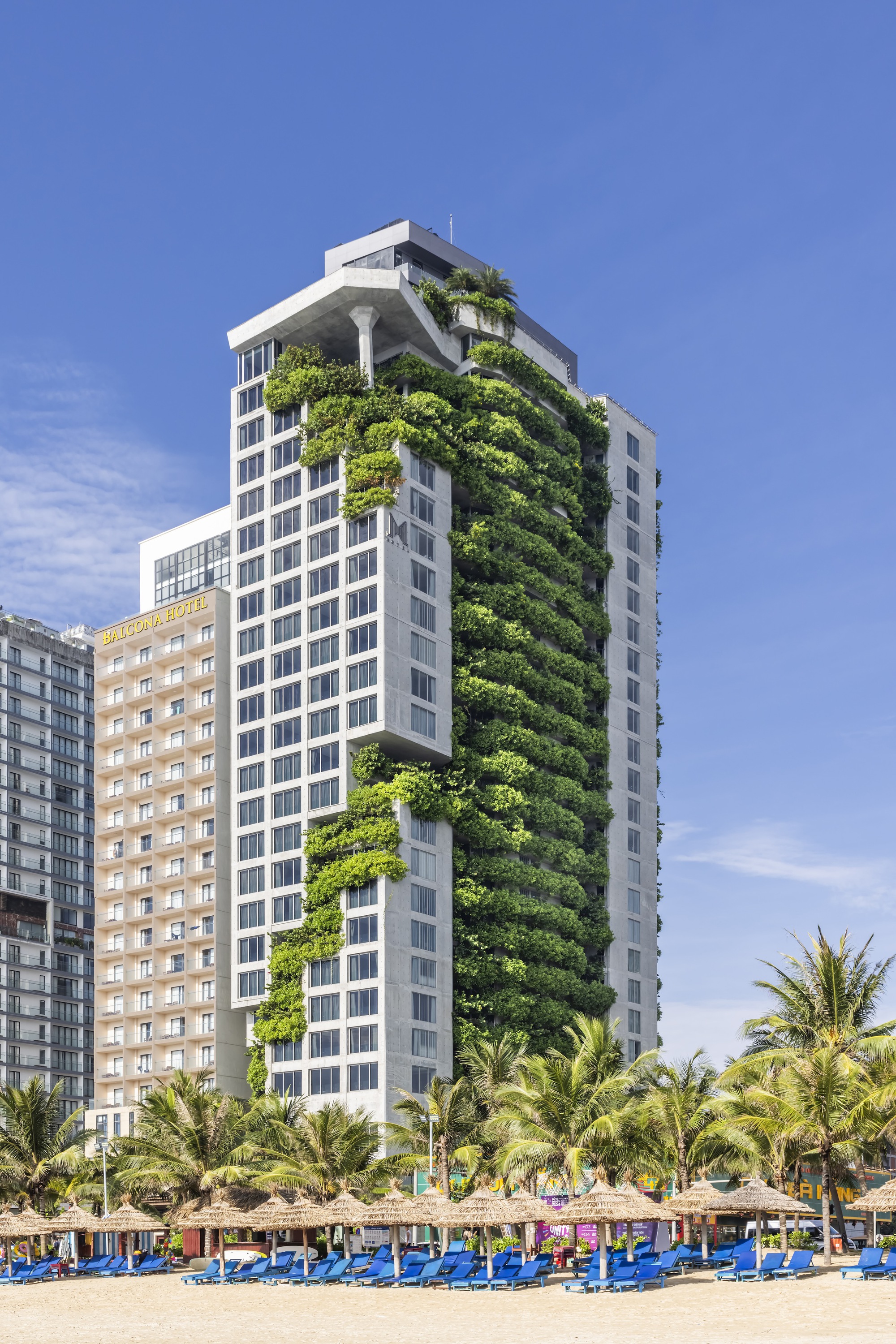 Portrait of the M Hotel facade with greenery cascading down the tower