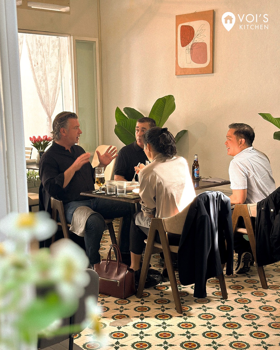 Diners chatting at a table in the plant-filled dining room at Voi's Kitchen